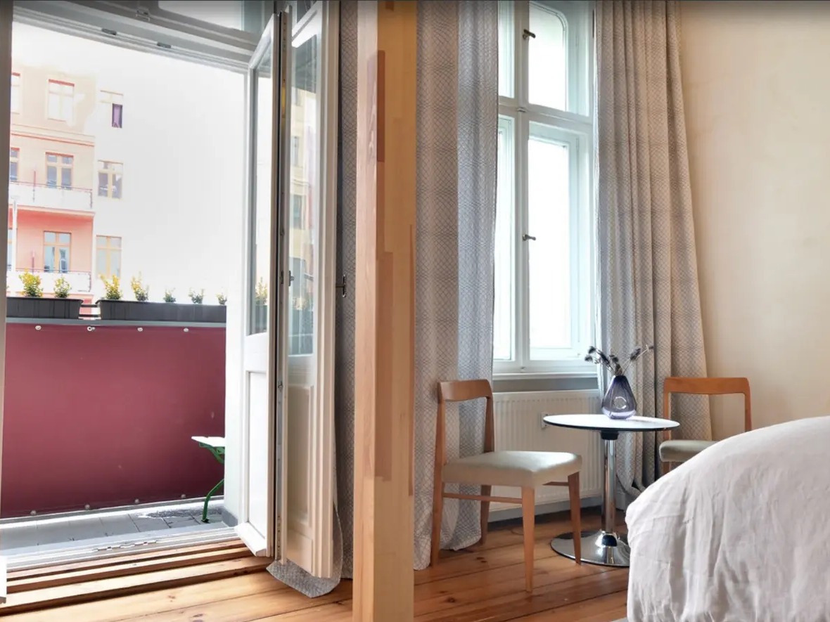A guest room at Linnen Hotel with open balcony doors onto Eberswalder Straße